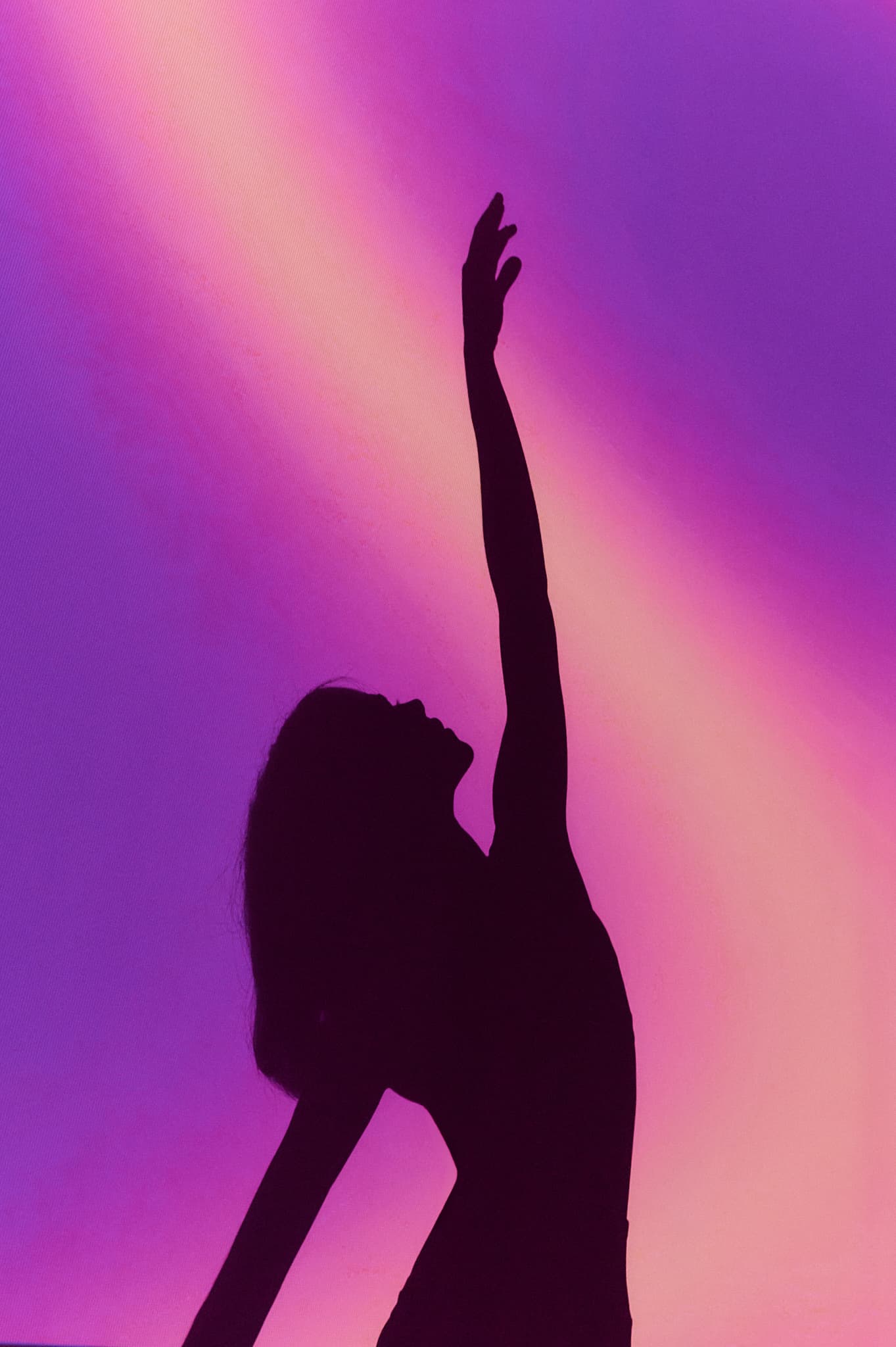 Silueta de mujer estirándose en estudio AAURA con iluminación púrpura