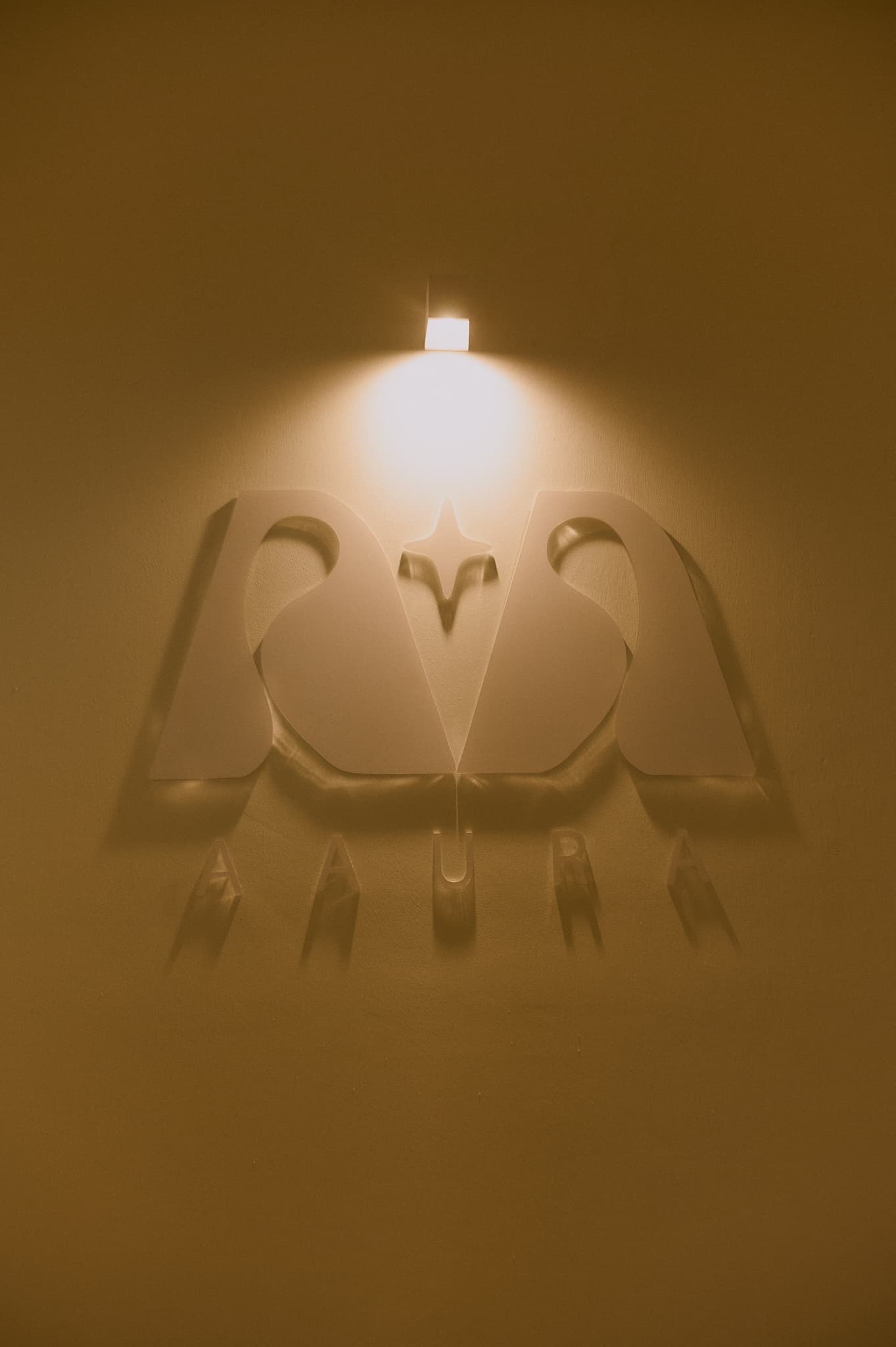 Logo AAURA iluminado en la pared del estudio