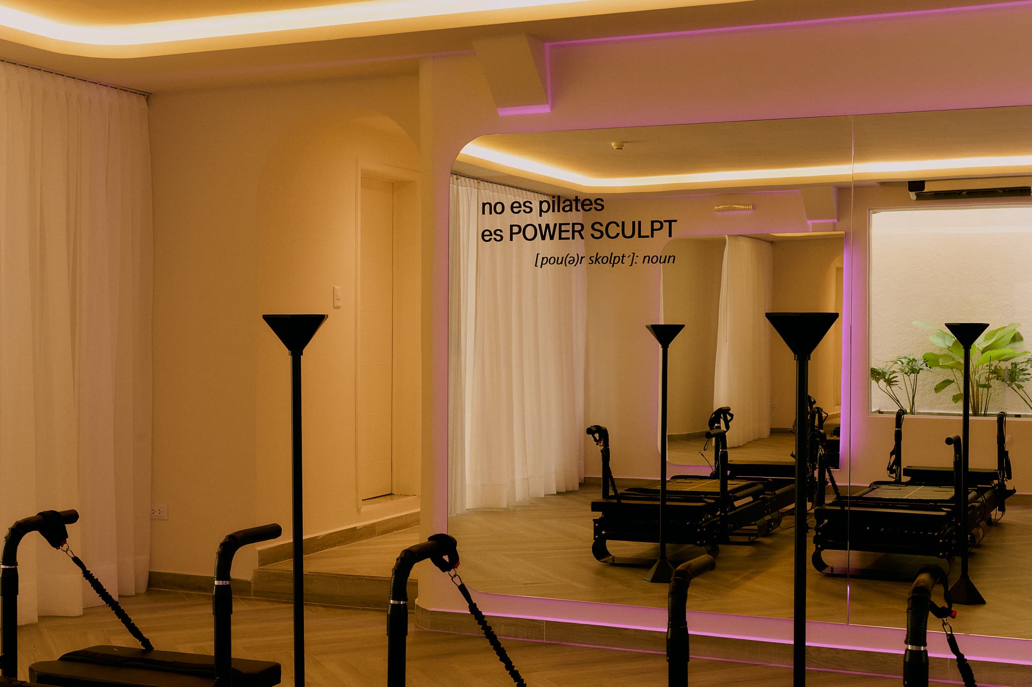 Espejo del estudio AAURA con el texto 'no es pilates, es POWER SCULPT' y máquinas Sculptformer